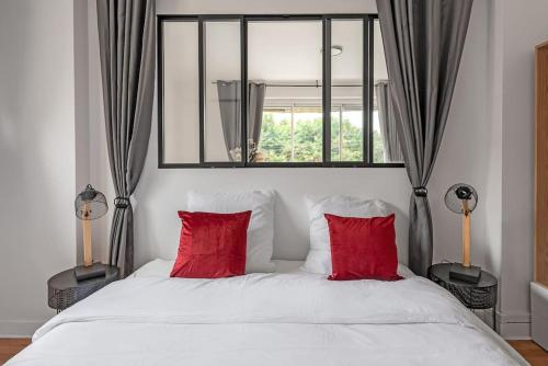 - un lit blanc avec des oreillers rouges et une fenêtre dans l'établissement L'Élégance Urbaine-clim-parking gratuit dans rue, à Toulouse