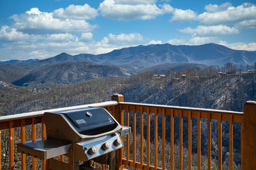 a grill on a balcony with a view of mountains at The Bear and Trout by Stony Brook Cabins in Gatlinburg