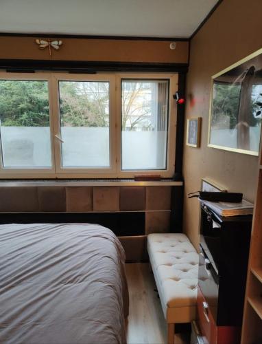 - une chambre avec des fenêtres, un lit et un banc dans l'établissement Libellule industrie, à Massy