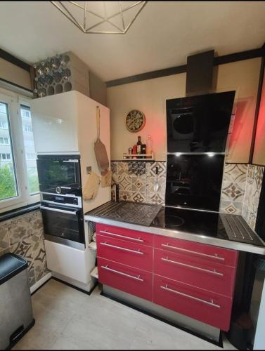 Il comprend une cuisine équipée d'une cuisinière rouge et blanche. four supérieur dans l'établissement Libellule industrie, à Massy