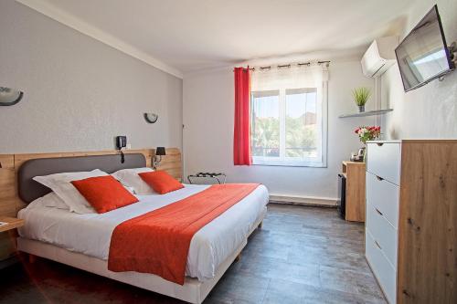 une chambre avec un lit avec des oreillers orange et une fenêtre dans l'établissement Azur Hôtel, à Balaruc-les-Bains