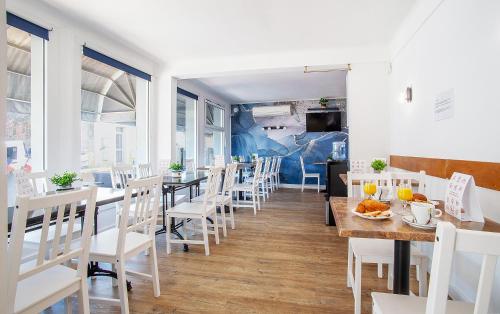 un restaurant avec des chaises blanches, des tables et des fenêtres dans l'établissement Azur Hôtel, à Balaruc-les-Bains