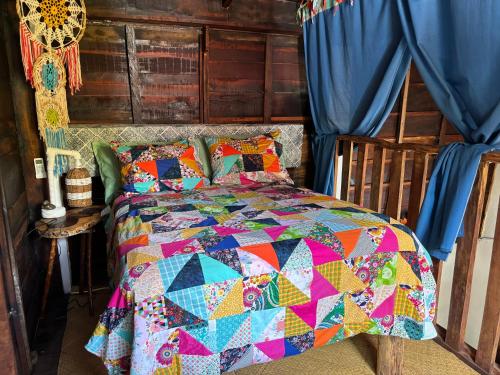 a bedroom with a bed with a colorful quilt at Cabana Bacalar in Bacalar