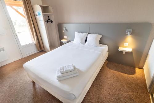 a large white bed in a room with a window at Kyriad Direct Auxerre - Appoigny in Appoigny
