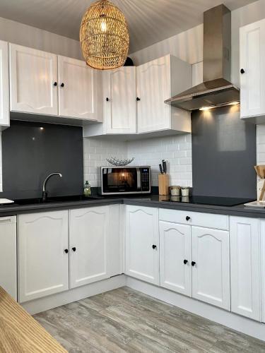 une cuisine avec des armoires blanches et un micro-ondes dans l'établissement Cozy studio completely renovated with breathtaking views of the port, à Saint-Martin-de-Ré