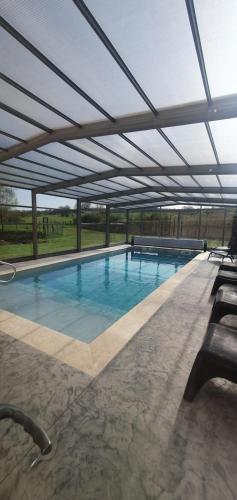 a large swimming pool with an open roof at Les Granges d'En Naoua, Grand gite avec Piscine in Maubec
