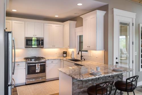 a kitchen with white cabinets and a marble counter top at Just Perfect By Stony Brook Cabins in Gatlinburg