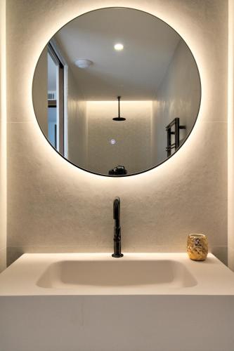 La salle de bains est pourvue d'un lavabo et d'un miroir rond. dans l'établissement Blue Diamond - 8 personnes - 5*, aux Issambres