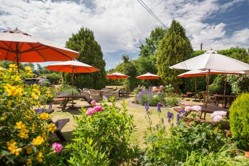 a garden with tables and umbrellas and flowers at Bedford Arms Hotel in Rickmansworth