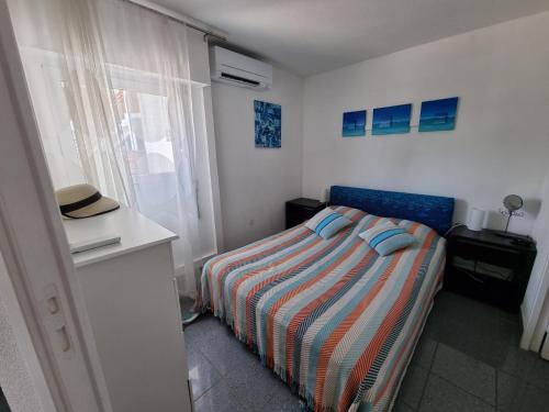 - une petite chambre avec un lit et une couverture rayée dans l'établissement appartement avec terrasse tropézienne, à Fréjus