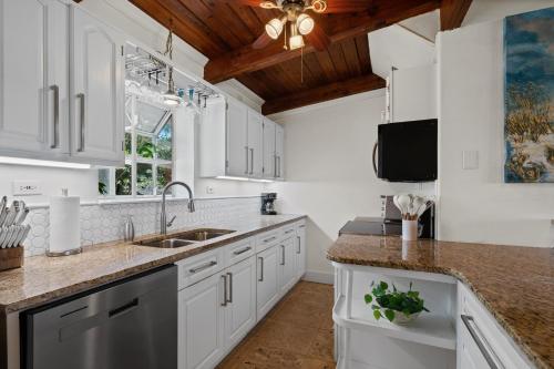 a kitchen with white cabinets and a sink at Sunset Vista Beach House in Pensacola Beach