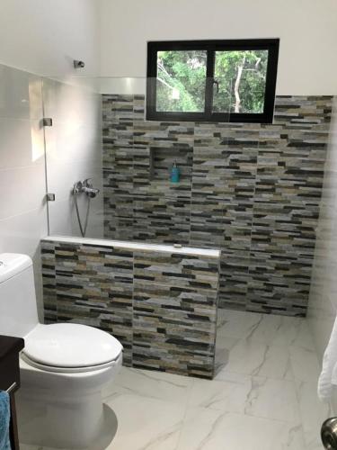a bathroom with a toilet and a stone wall at Villa Luce in Las Terrenas