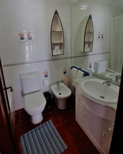 a bathroom with a toilet and a sink and mirror at Vila T2 Algarve piscina privada in Vila Nova De Cacela