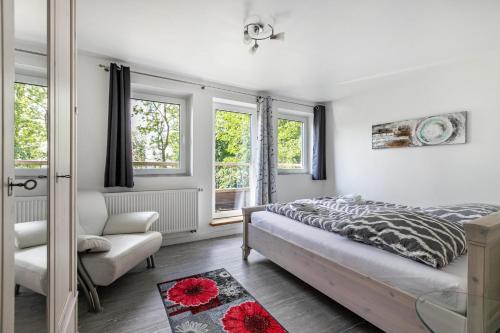 a bedroom with a bed and a chair and windows at Rømø in Galmsbüll