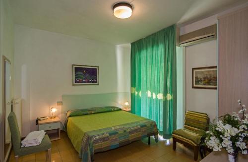 a bedroom with a green bed and a chair at Hotel San Domingo in Lido di Camaiore