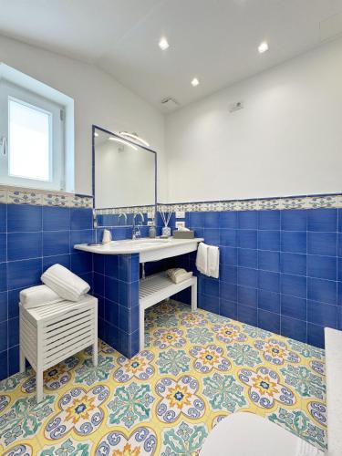 a blue tiled bathroom with a sink and a mirror at Aria - Suite in Capri in Capri