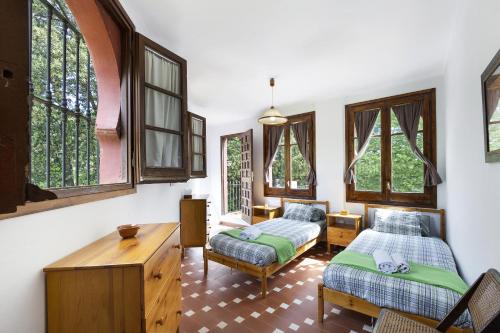 um quarto com 2 camas, uma mesa e janelas em El Cortijo em Arenys de Munt