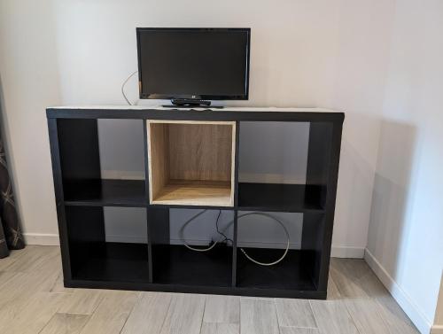 a black book shelf with a tv on top at La Chataigneraie in Châtenois