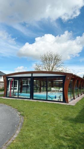 une maison avec une piscine au milieu d'un champ dans l'établissement Gîte avec piscine, à Lestrem