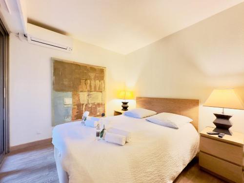 - une chambre avec 2 lits avec des draps blancs et 2 lampes dans l'établissement L'ébène - Cannes Centre - Cozy, à Cannes