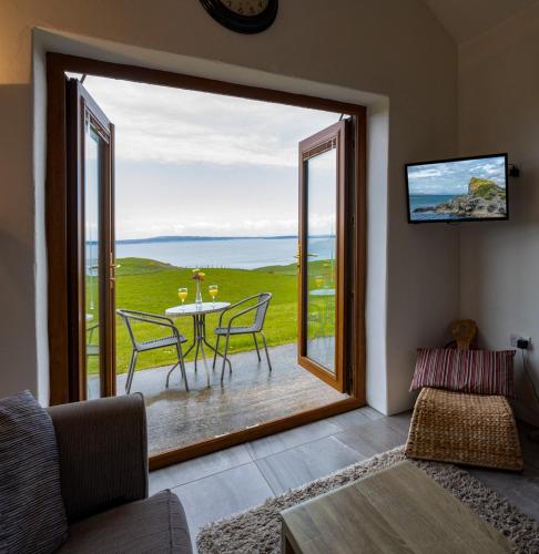 a living room with a table and chairs and a large window at Stable Cottage - Kinbane Self Catering Cottages in Ballintoy