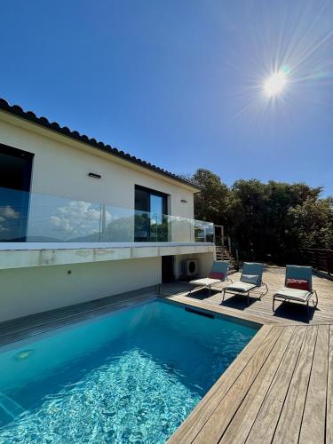 une maison avec une piscine et deux chaises sur une terrasse dans l'établissement La Villa Julea, à Olmeto