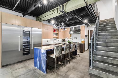 a kitchen with a counter with chairs and a refrigerator at NEW Luxury Concrete Home Just Minutes from the Beach in Long Beach