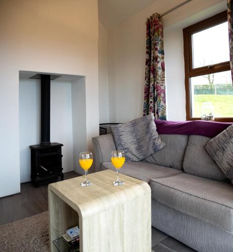 a living room with a couch and two wine glasses on a table at Stable Cottage - Kinbane Self Catering Cottages in Ballintoy