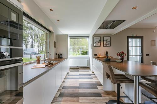 a kitchen with white cabinets and a large window at Huswell - Holiday home along the canal with great views in Damme
