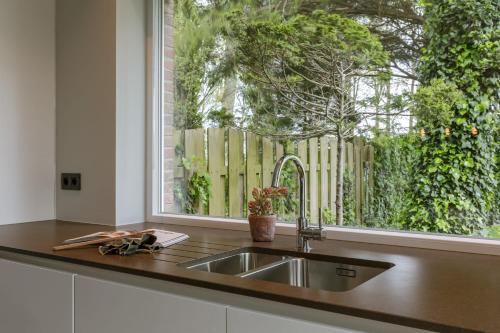 a kitchen counter with a sink and a window at Huswell - Holiday home along the canal with great views in Damme