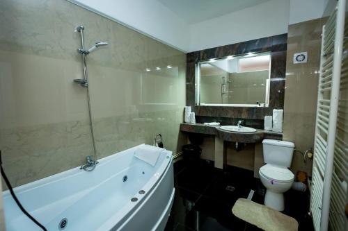 a bathroom with a tub and a toilet and a sink at Grand Hotel Baroc in Zalău