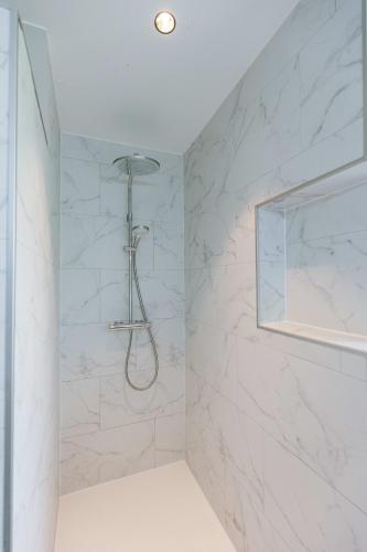 a shower in a bathroom with white marble walls at Huswell - Holiday home along the canal with great views in Damme