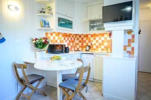 - une cuisine avec une table et des chaises blanches dans l'établissement Nice and quiet appartment only 2 steps away from the harbour of St Martin, à Saint-Martin-de-Ré