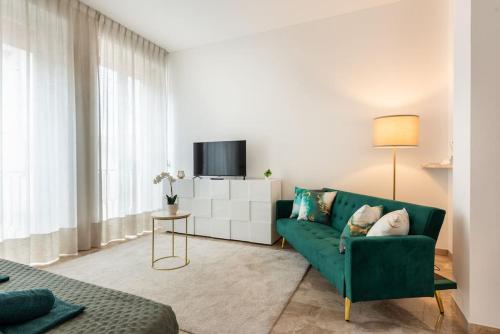 a living room with a green couch and a tv at Appartamento vicino Milano, Como e MXP in Busto Arsizio