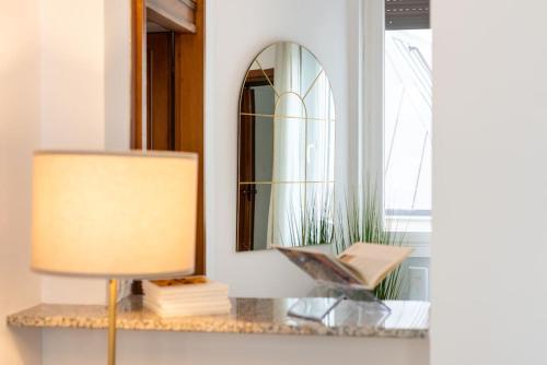 a table with a lamp and a mirror at Appartamento vicino Milano, Como e MXP in Busto Arsizio