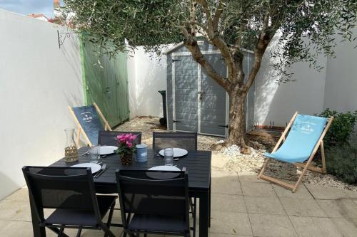 une table noire et des chaises et un arbre dans l'établissement Charming house with garden in the heart of Saint Martin, à Saint-Martin-de-Ré