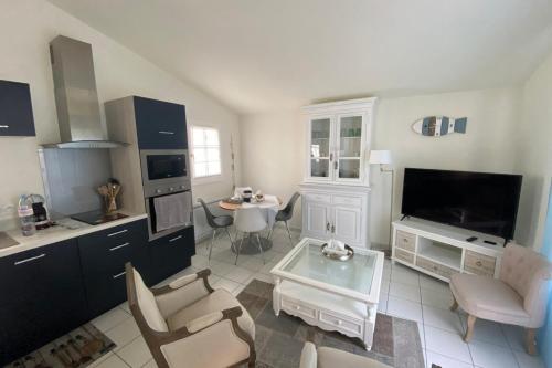 cocina con sala de estar con TV y mesa en Charming house with garden in the heart of Saint Martin, en Saint-Martin-de-Ré