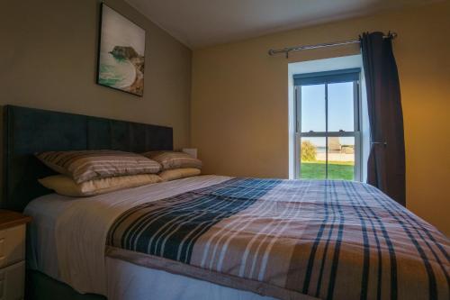 Schlafzimmer mit einem Bett und einem Fenster in der Unterkunft Carrig Island Lodge in Ballylongford