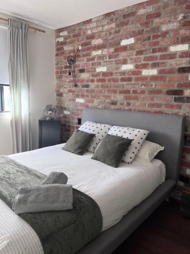a bedroom with a brick wall and a bed at T h e L o f t - Stunning private apartment in Perth