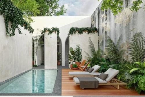 a swimming pool with two lounge chairs and a house at TIKUL EN Merida HISTORIC CENTER in Mérida
