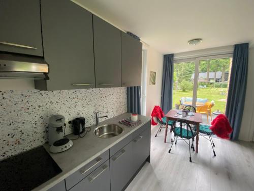 een keuken met een wastafel en een tafel met stoelen bij Camping Het Vossenhol in Ermelo