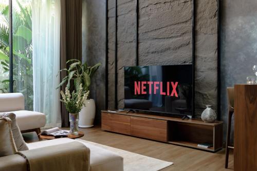a living room with a television with the netflix sign on it at Sunny Cuddles in Canggu