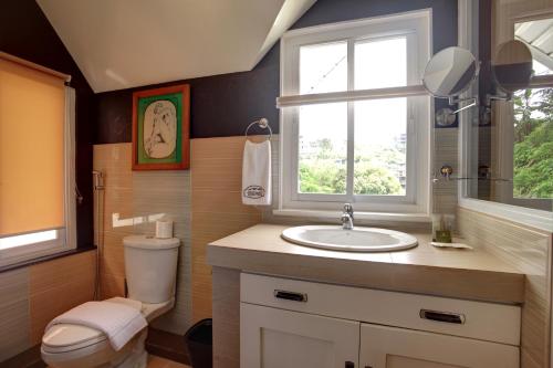 uma casa de banho com um lavatório, um WC e uma janela. em Guest Haven Chalet em Baguio