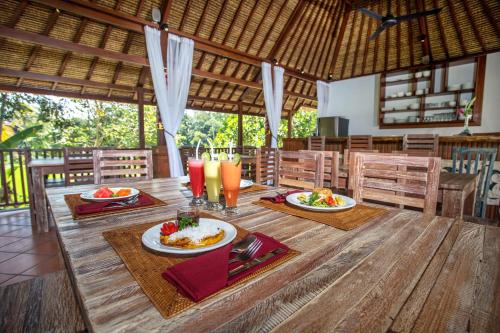 Una mesa de madera con platos de comida encima. en Ubud Luwih Nature Retreat, en Ubud