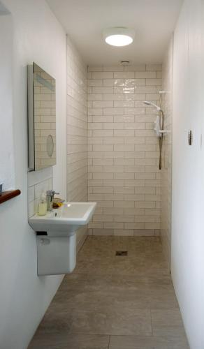 a white bathroom with a sink and a shower at Kinbane Self Catering Cottages - 'Makem's Cottage' in Ballycastle