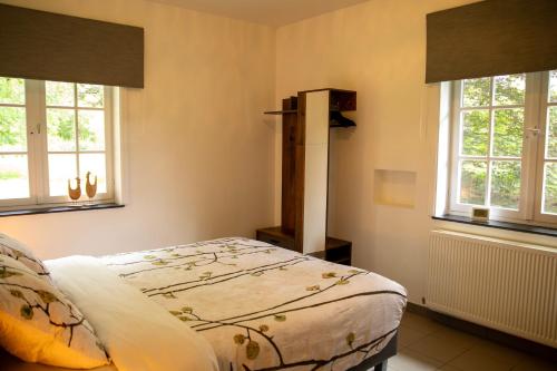 a bedroom with a bed and two windows at Tussen Heide en Bos in het Nationaal Park Hoge Kempen in Oudsbergen 