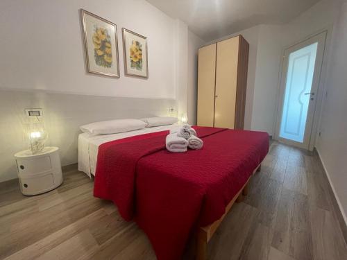 a bedroom with a bed with a stuffed animal on a red blanket at Appartamento Dragunara in Alghero