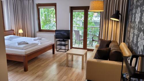 a bedroom with a bed and a couch and a tv at Villa Melodia in Świnoujście