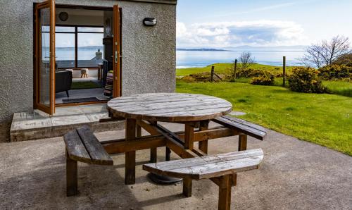 a picnic table and benches in front of a house at Kinbane Self Catering Cottages - 'Makem's Cottage' in Ballycastle