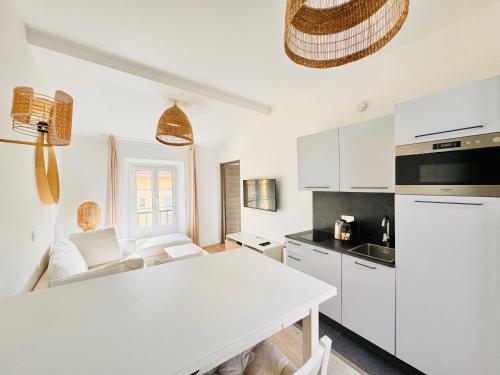 une cuisine avec des armoires blanches et une table blanche dans l'établissement Le Bohème - Logement Cozy centre, à Cannes
